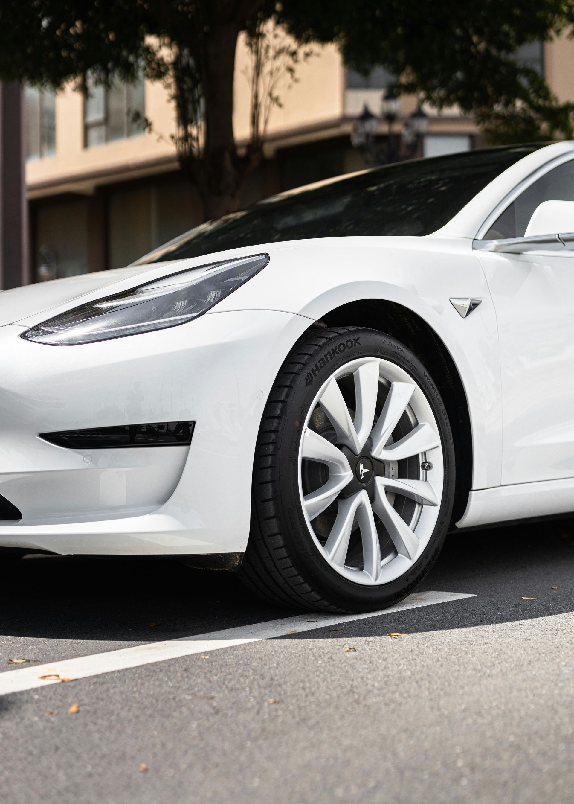 White Tesla Model 3 car parked on a city street.