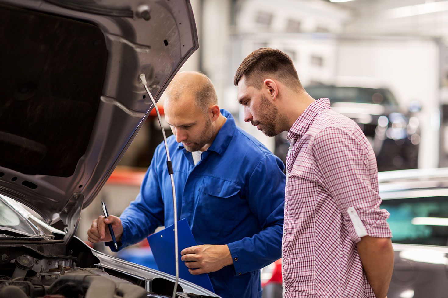 auto-mechanic-with-clipboard-and-man-at-car-shop